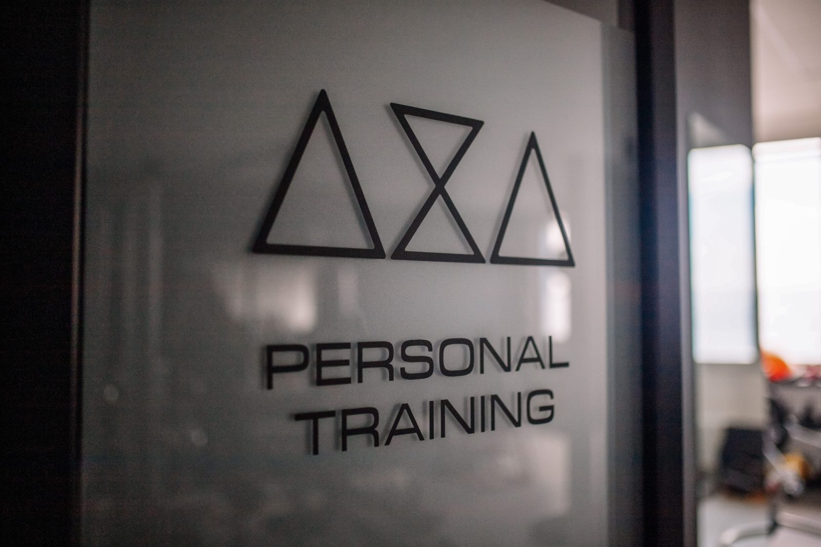 L'insegna «Personal Training» con il logo AXA Studio sulla vetrata della sala.