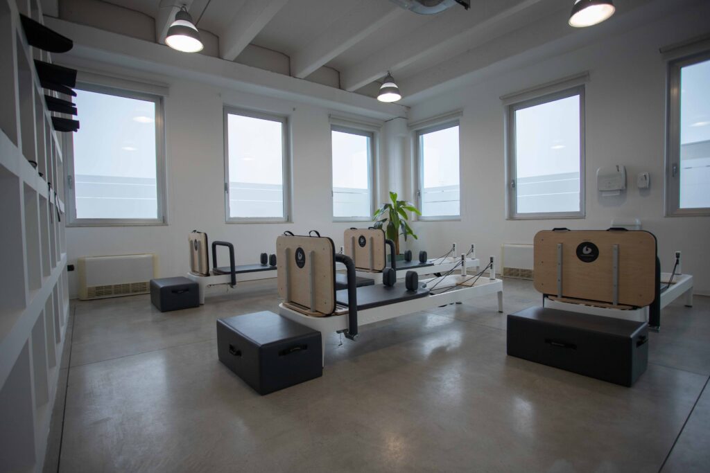 I reformer della sala pilates visti di lato, con la luce naturale dalle finestre.